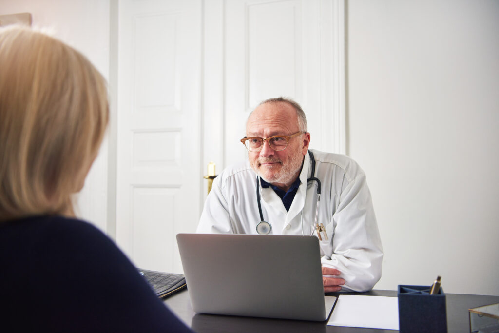 doctor with laptop talking to a senior woman