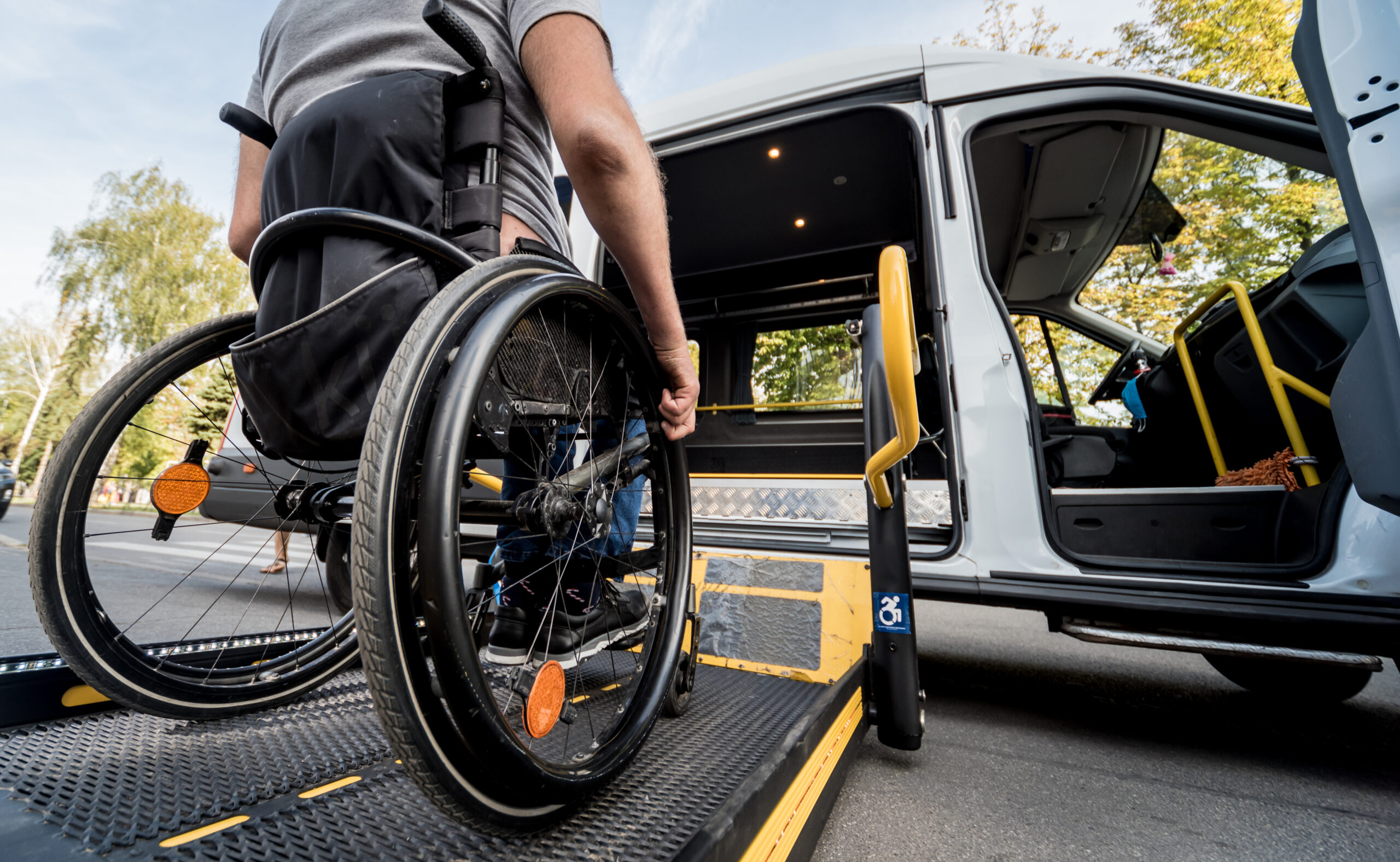 A man in a wheelchair moves to the lift of a specialized vehicle for people with disabilities.